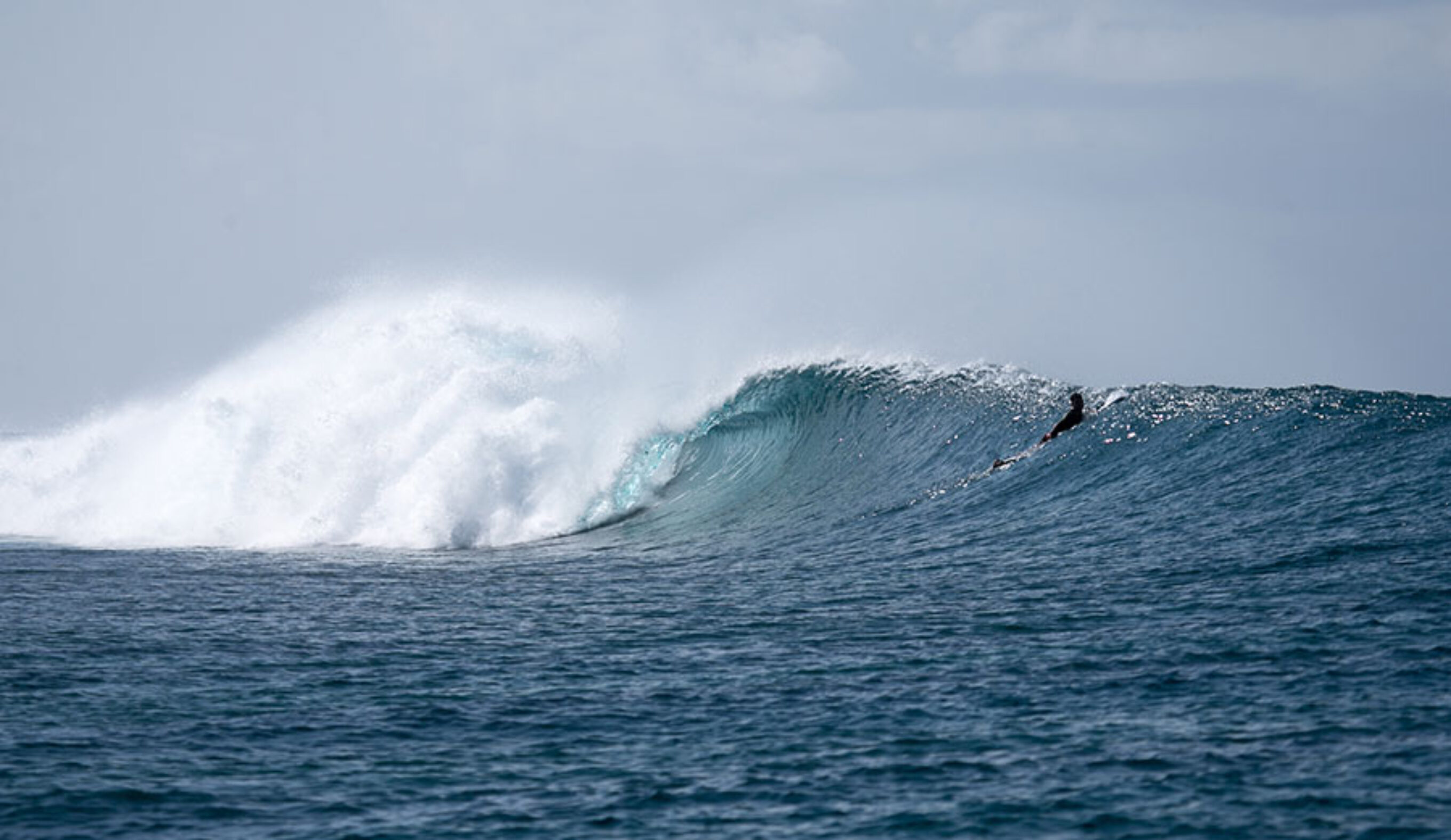 Wave in the Maldives with surfer watching
