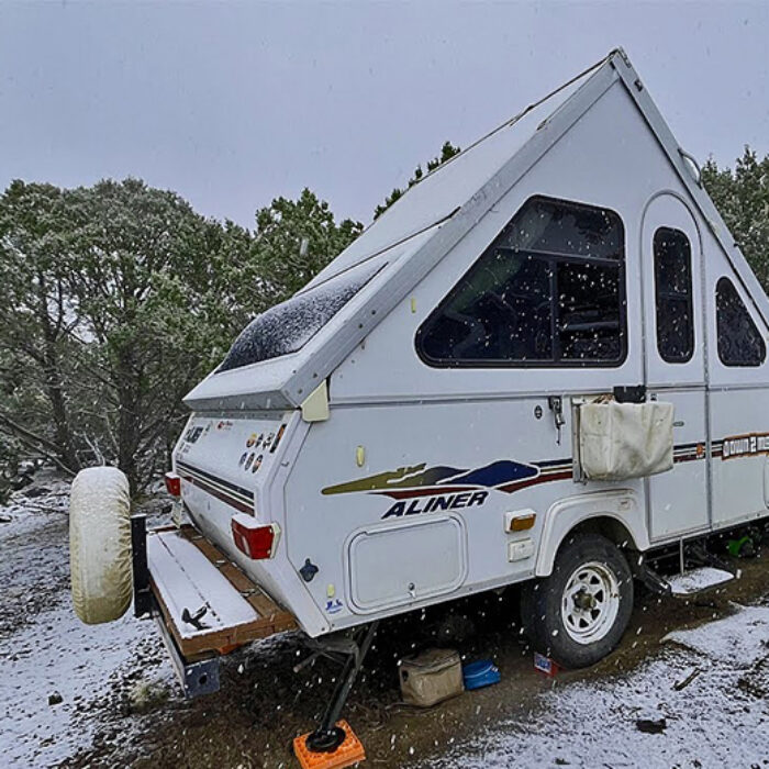 An A-Frame camper parked during a snow storm.