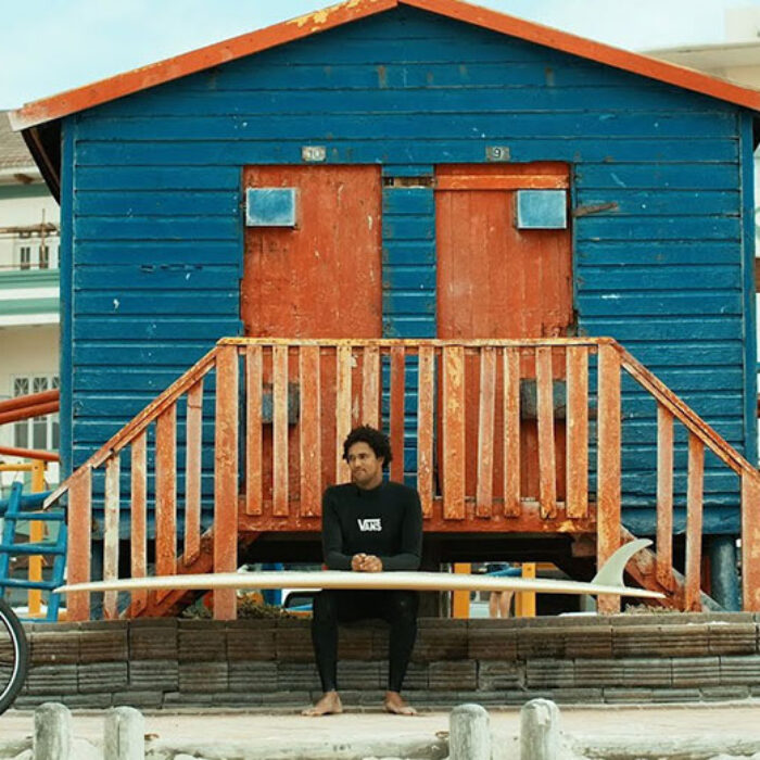 Mikey February sitting with surfboard