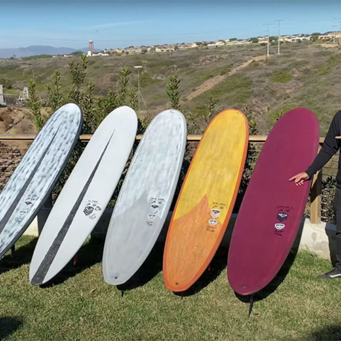 Taylor Jensen standing beside longboards