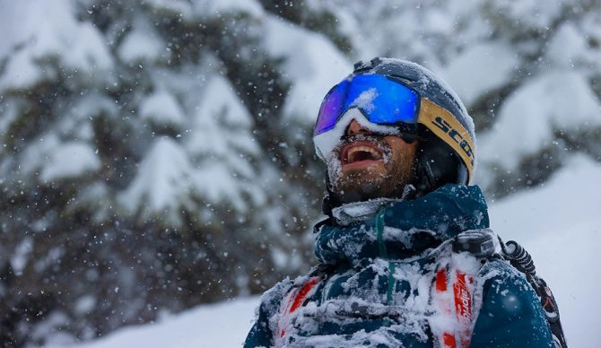 stoked dude in the snow with snow on his face skiing