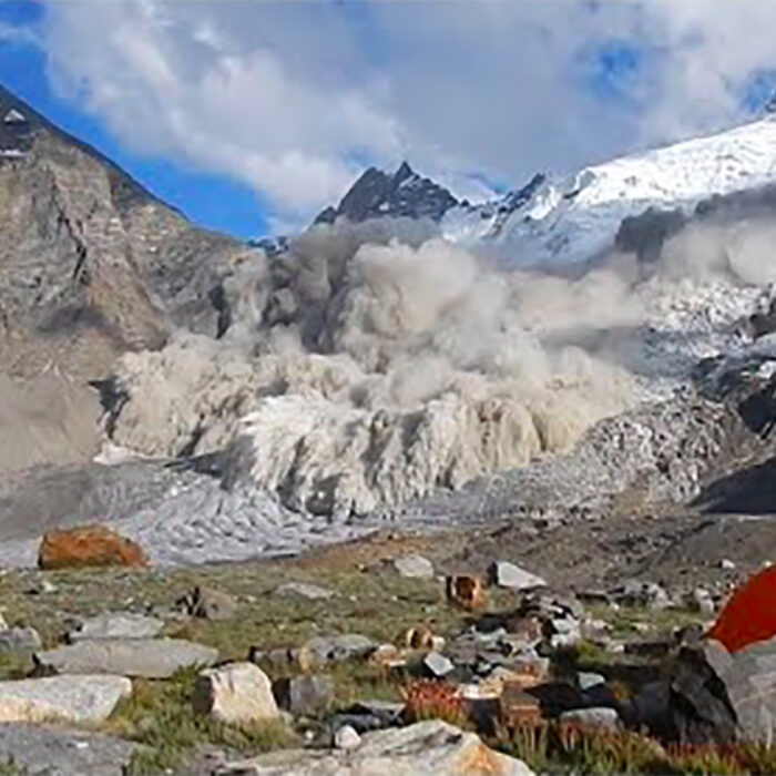 an avalanche rips down a valley in the Himalayas