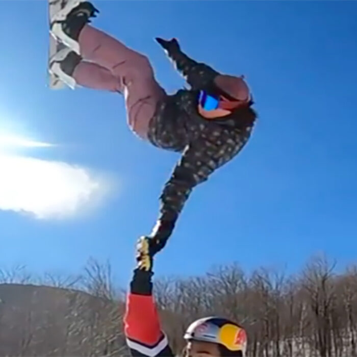 A snowboarder slaps a high five in mid air