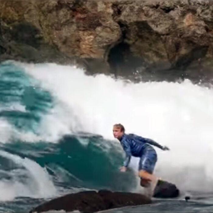 Jamie O'Brien surfs a wave at Shark's Cove right in front of a rock