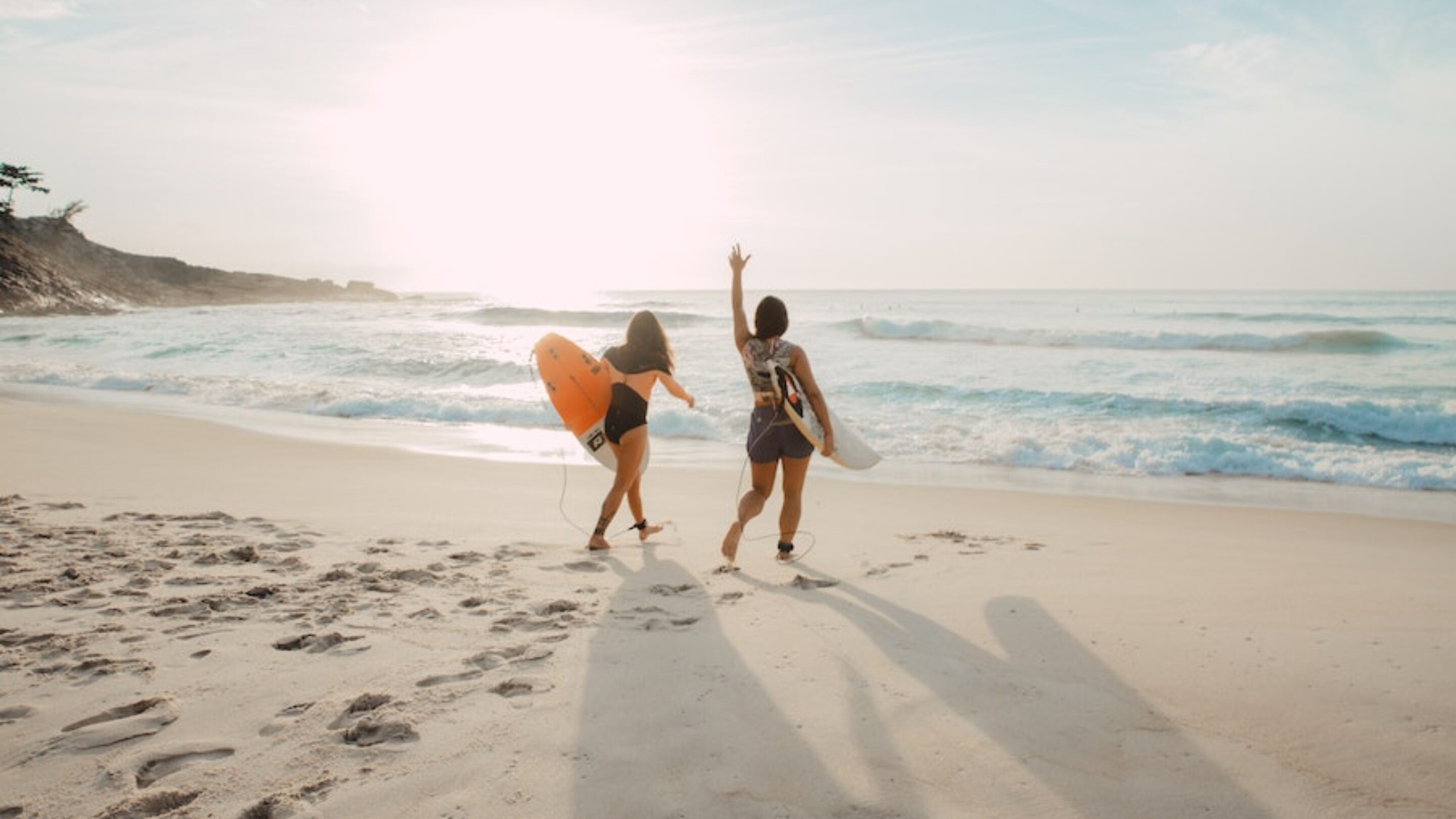 elizeu dias via unsplash two women surfers on the beach