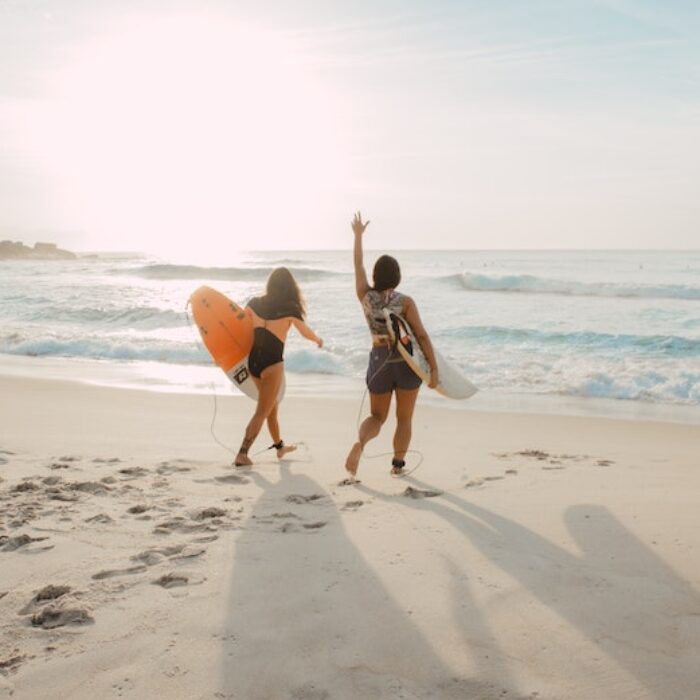 elizeu dias via unsplash two women surfers on the beach