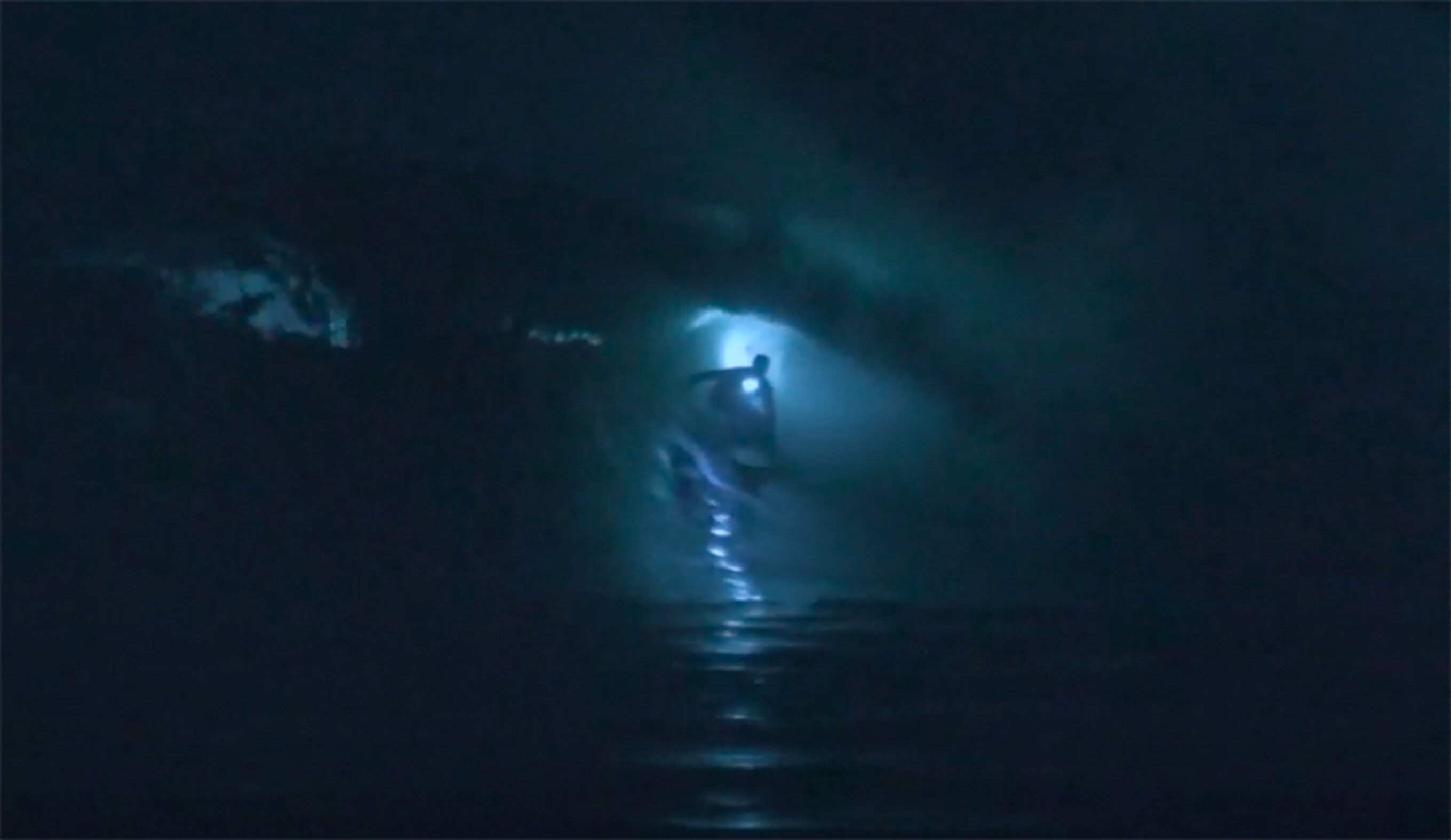 a surfer getting barreled at night