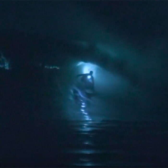 a surfer getting barreled at night