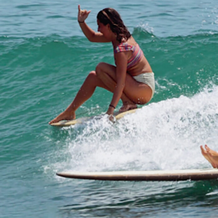 A girl throws a shaka while longboarding