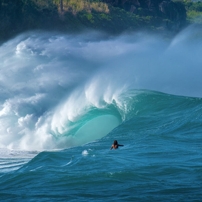 A surfer looks at a giant wave