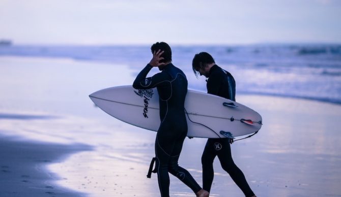 surfers on a beach holding ear unsplash