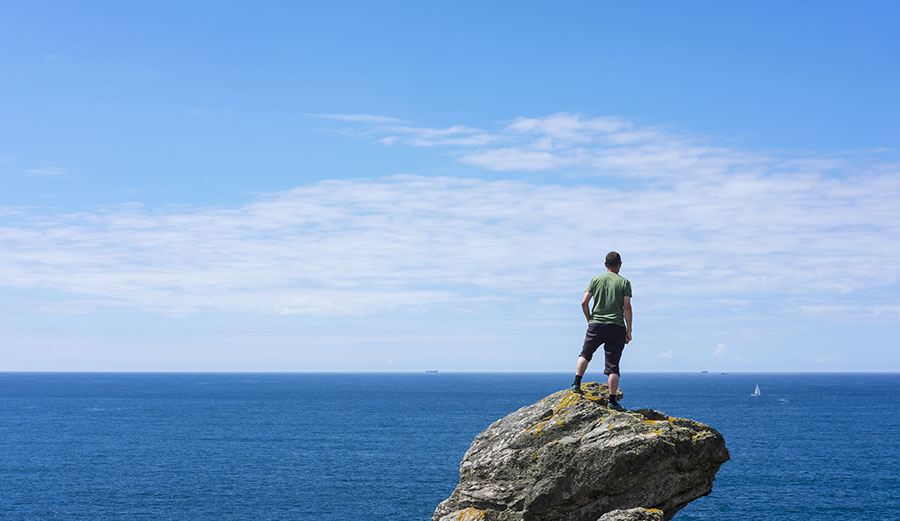 Man on rock looking at ocean