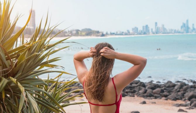 girl holding hair above surf break in australia