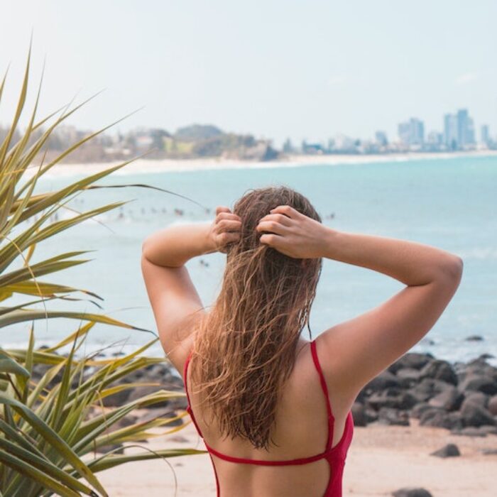 girl holding hair above surf break in australia