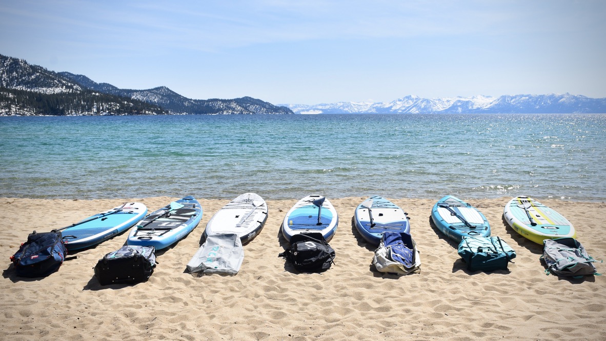 A lineup of the best inflatable paddles boards on the beach in front of lake tahoe