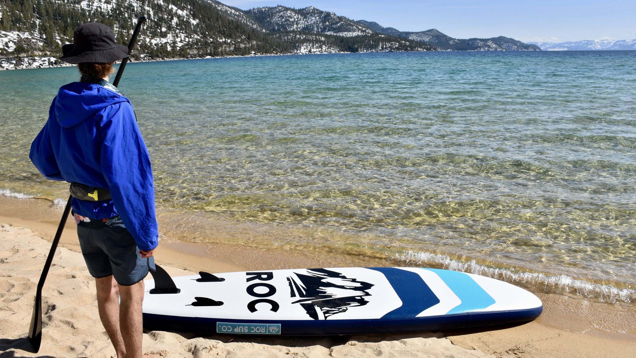 man preparing to paddle the roc kahuna inflatable paddle board on lake tahoe