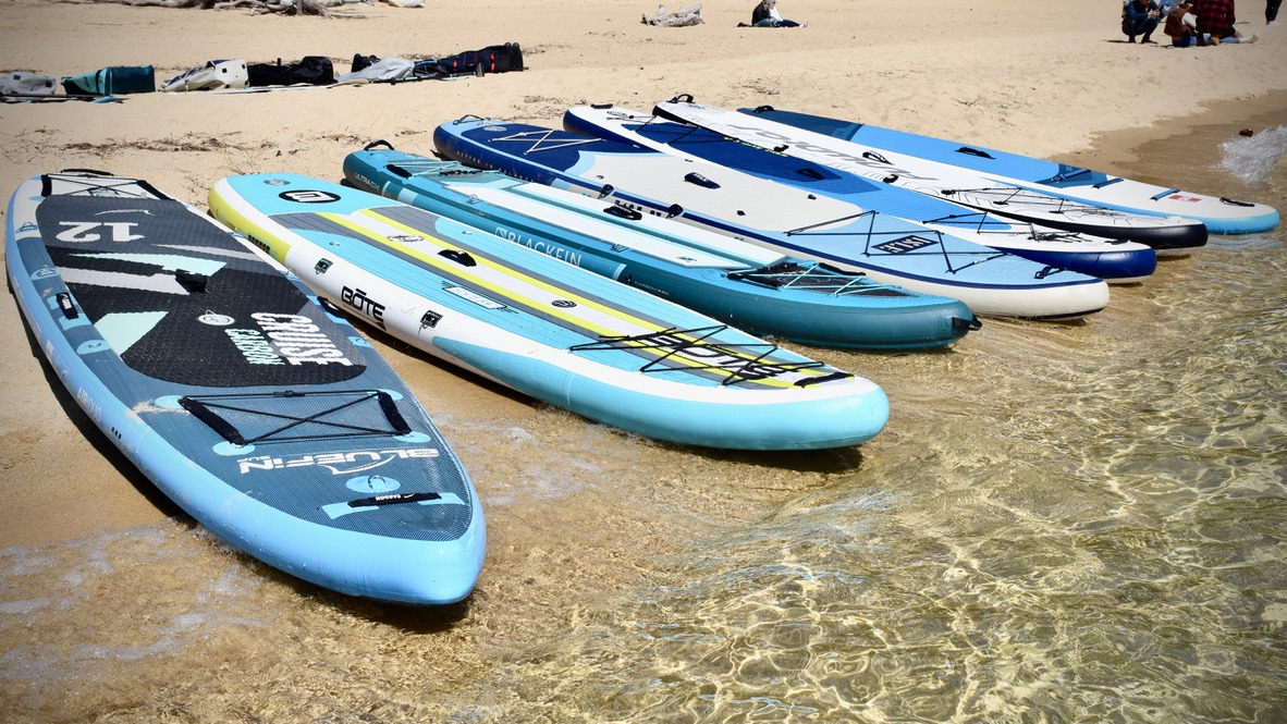 lineup of seven of the best inflatable paddle boards being tested on the beach at lake tahoe