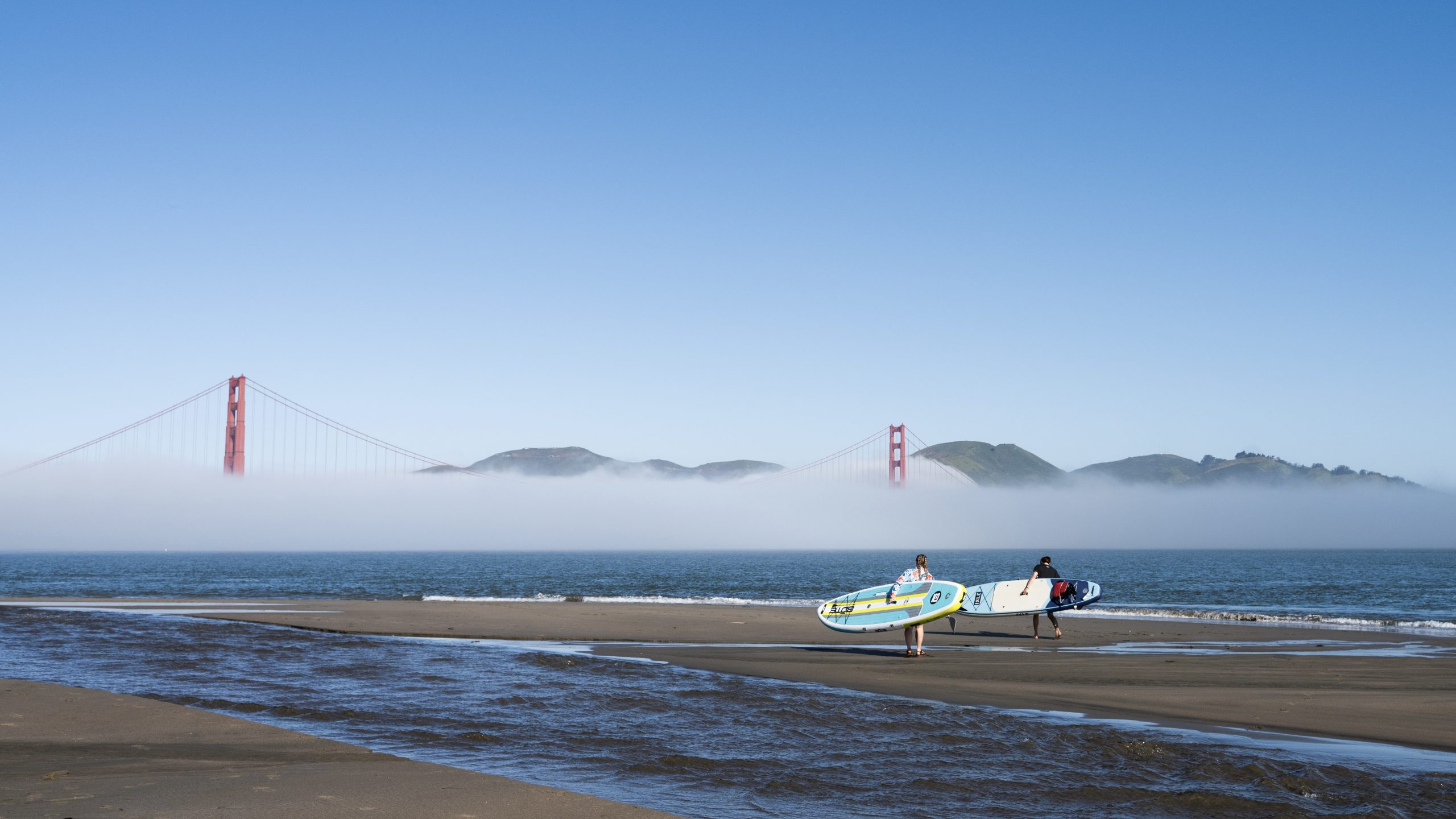 two testers paddling the bote breeze aero and isle explorer inflatable paddles boards in san francisco with golden gate bridge in the background