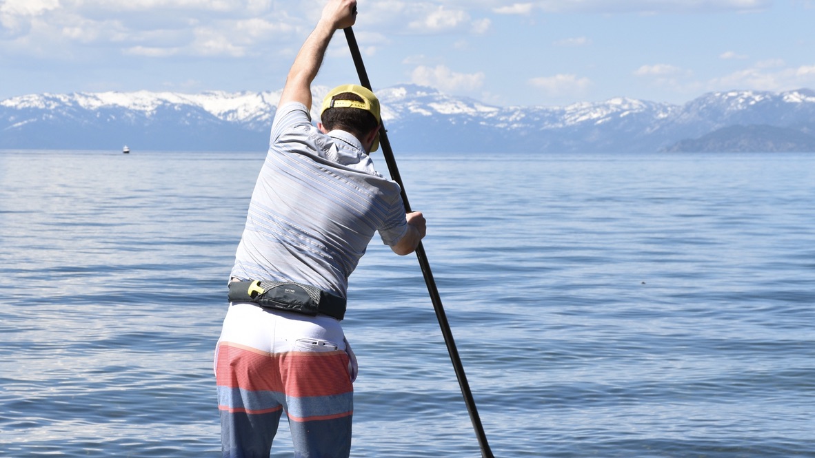 man paddle boarding on lake tahoe with the Onyx M-16 life jacket