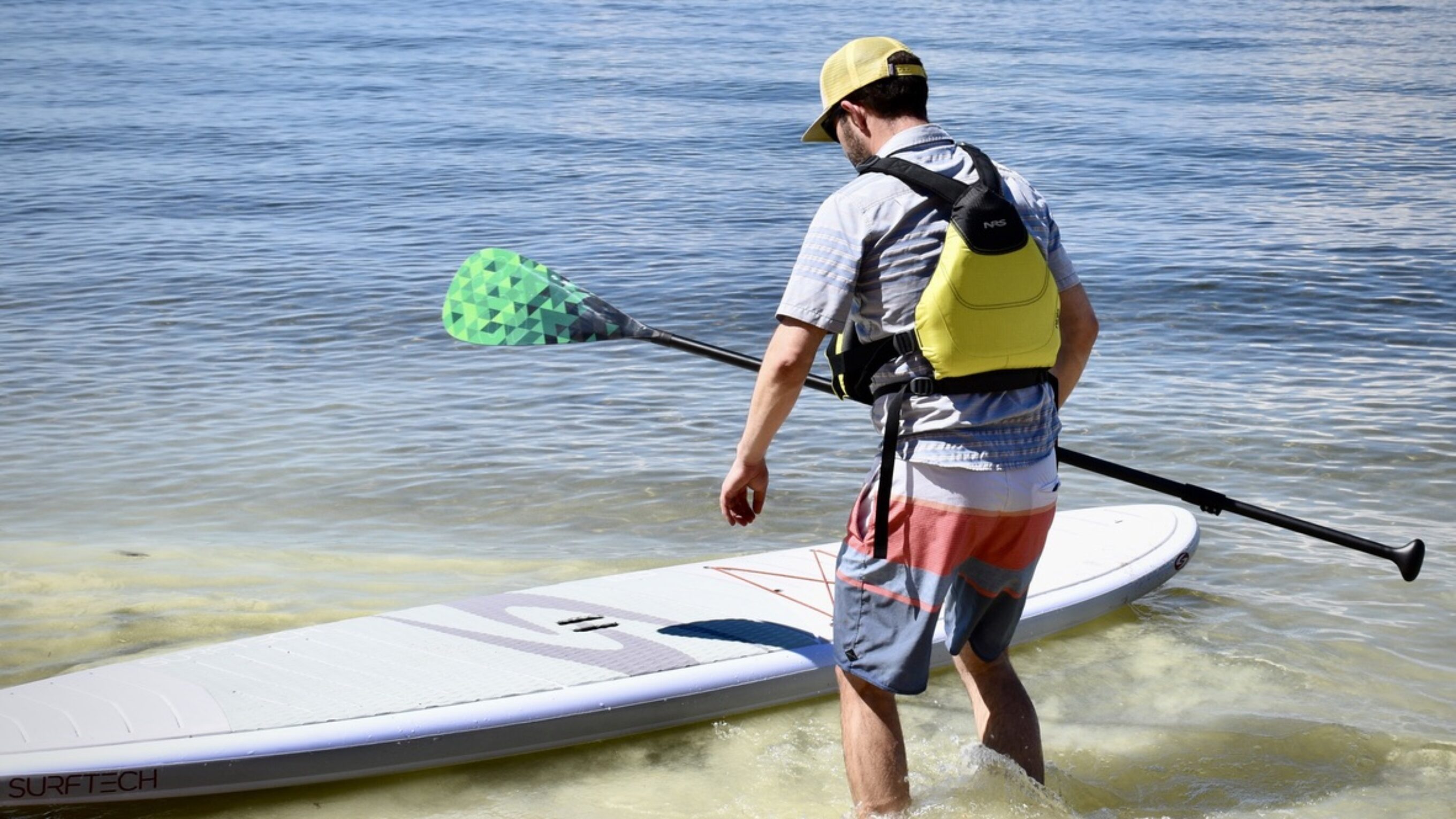 man paddle boarding on lake tahoe with NRS Ninja life jacket