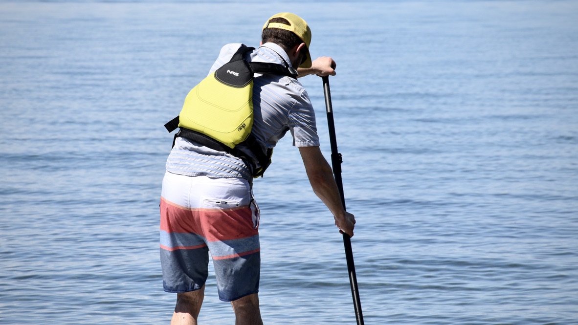 man paddle boarding on lake tahoe while wearing the NRS Ninja life jacket