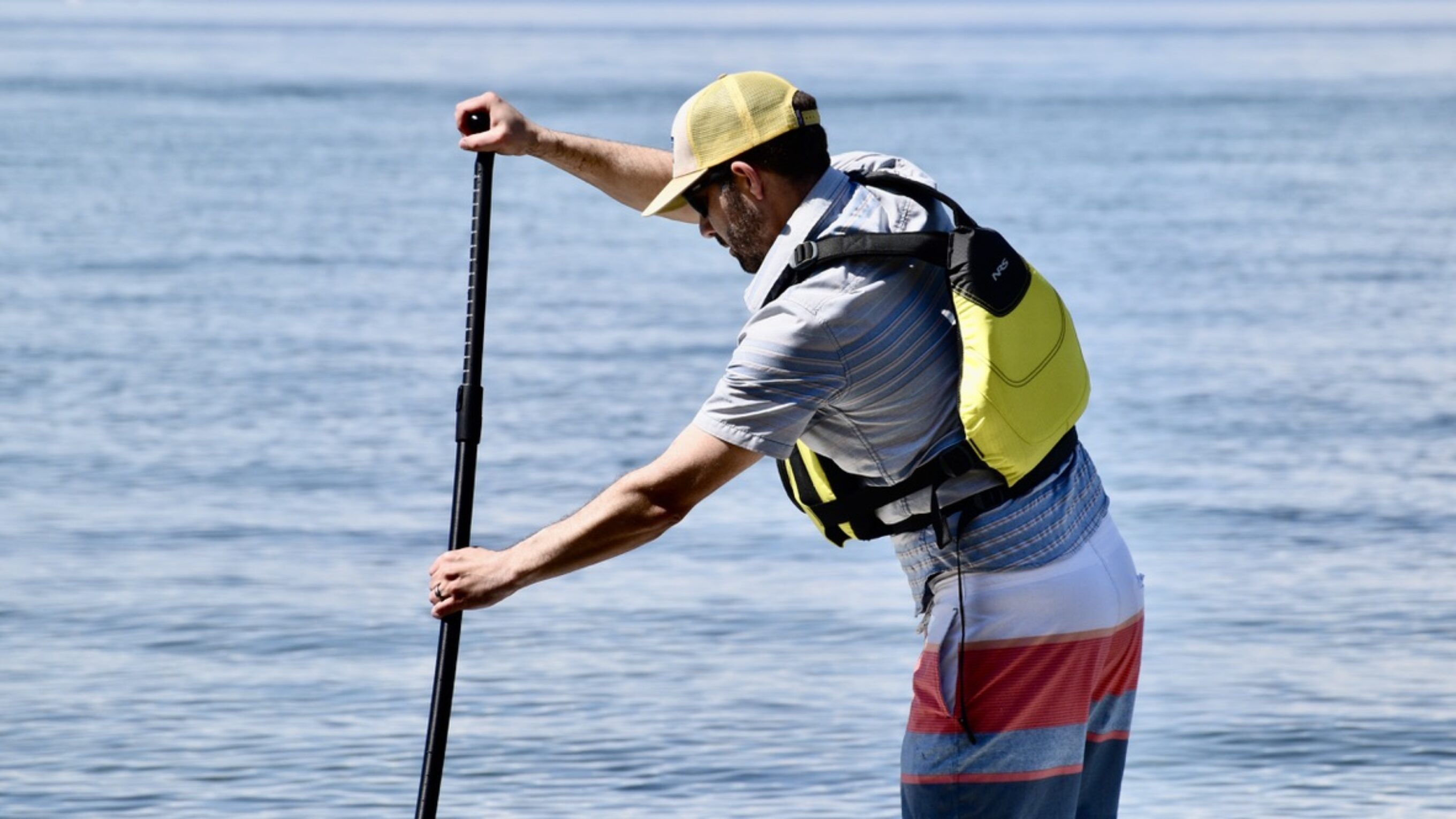 man paddle boarding on lake tahoe while wearing the NRS Ninja life jacket