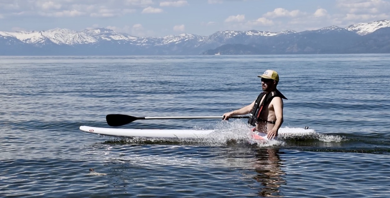 man falling off a paddle board into lake tahoe