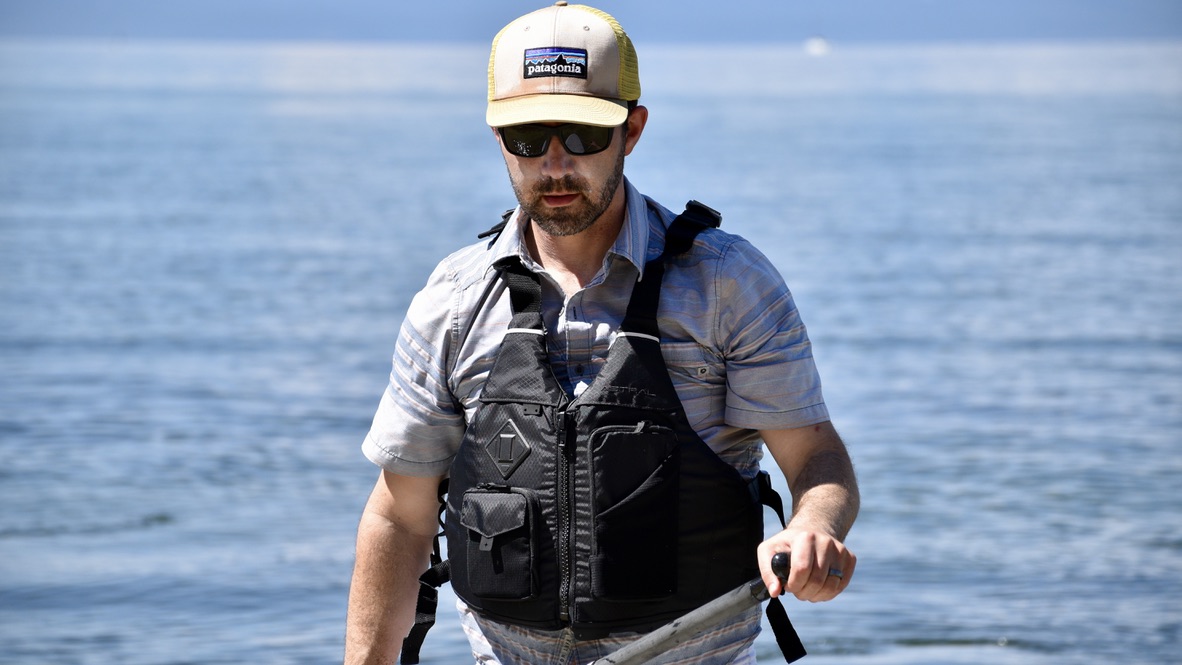 handsome man wearing the Astral E-Ronny life jacket while paddle boarding on lake tahoe