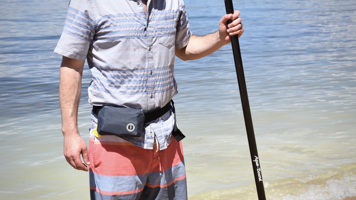 man wearing the mustang survival minimalist inflatable belt life jacket with lake tahoe in the background