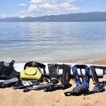 11 life jackets laying on a paddle board on the beach at lake tahoe