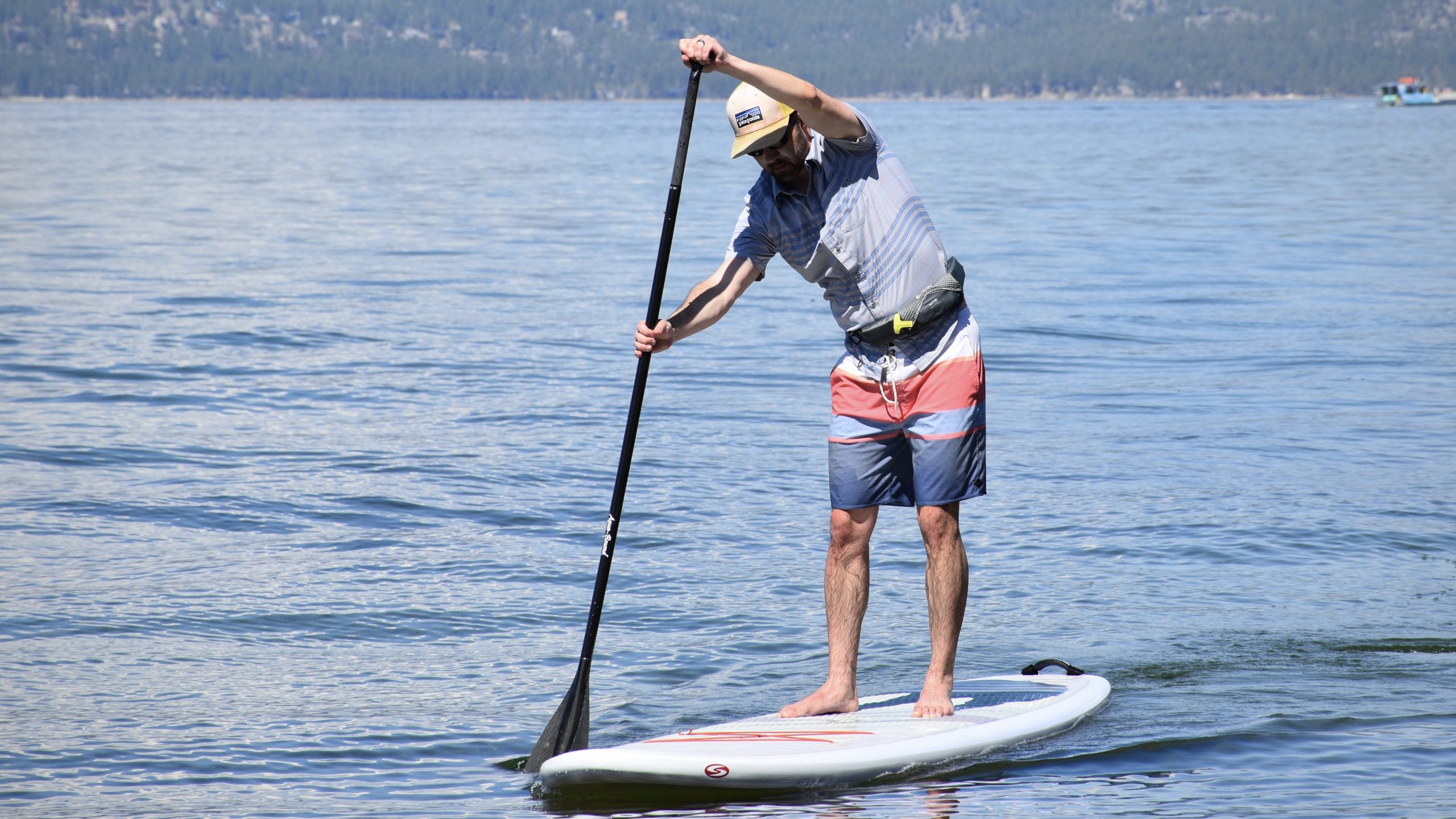 man paddle boarding on lake tahoe wearing the ony m-16 inflatable belt life jacket