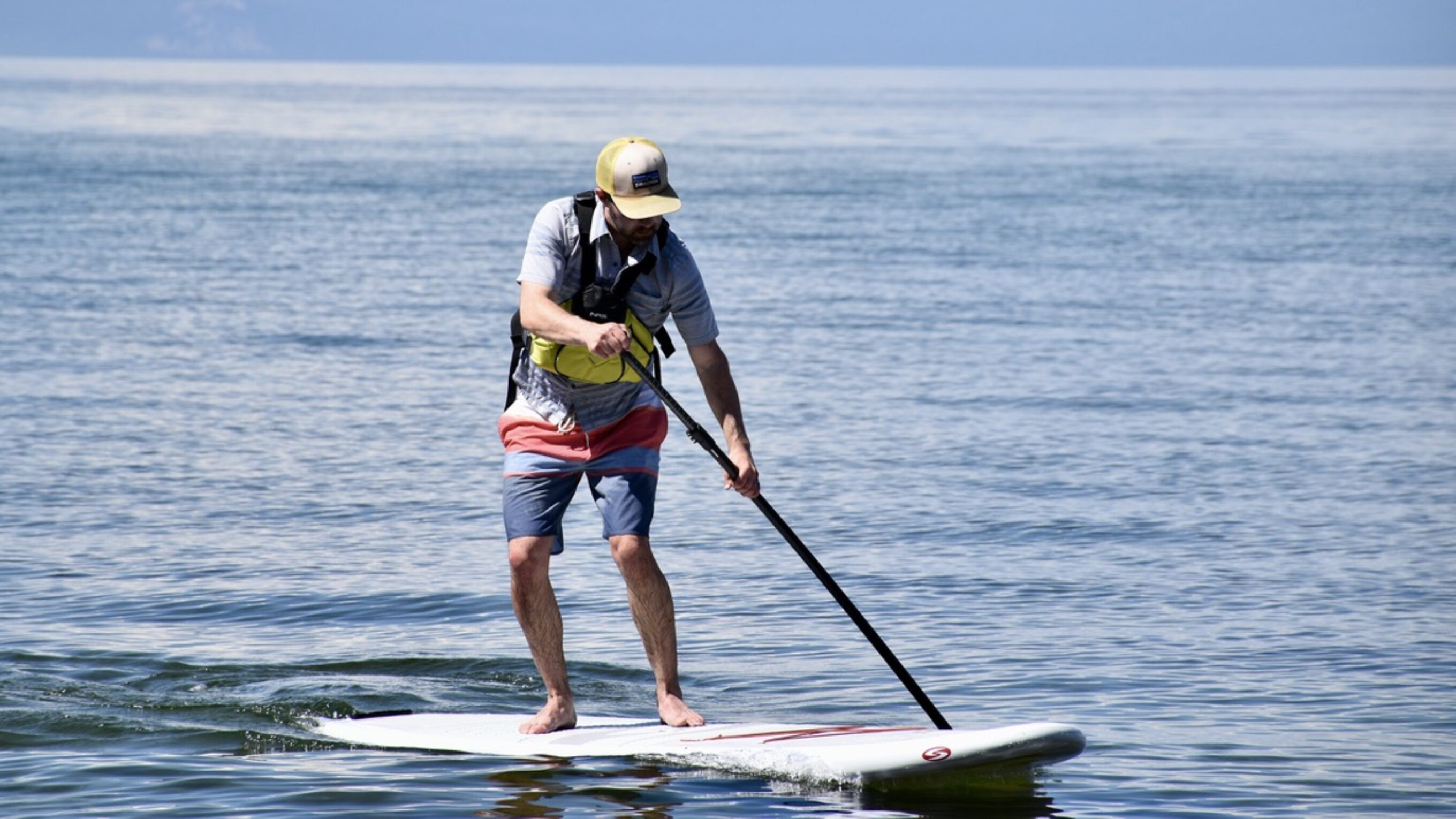 man paddle boarding on lake tahoe with the NRS Ninja life jacket