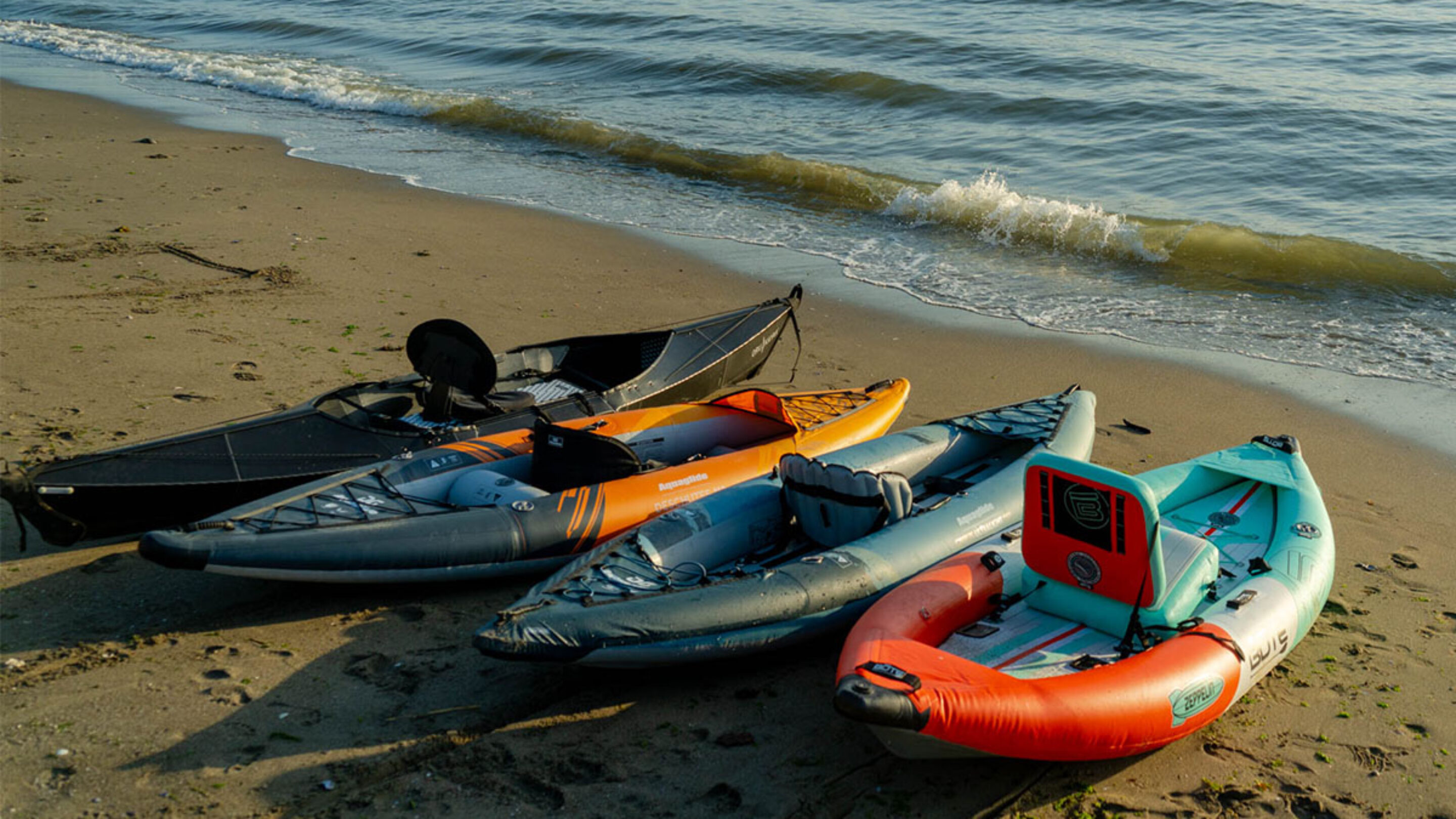 some of the kayaks we reviewed the best inflatable kayaks for 2023, shown here lined up on the beach.