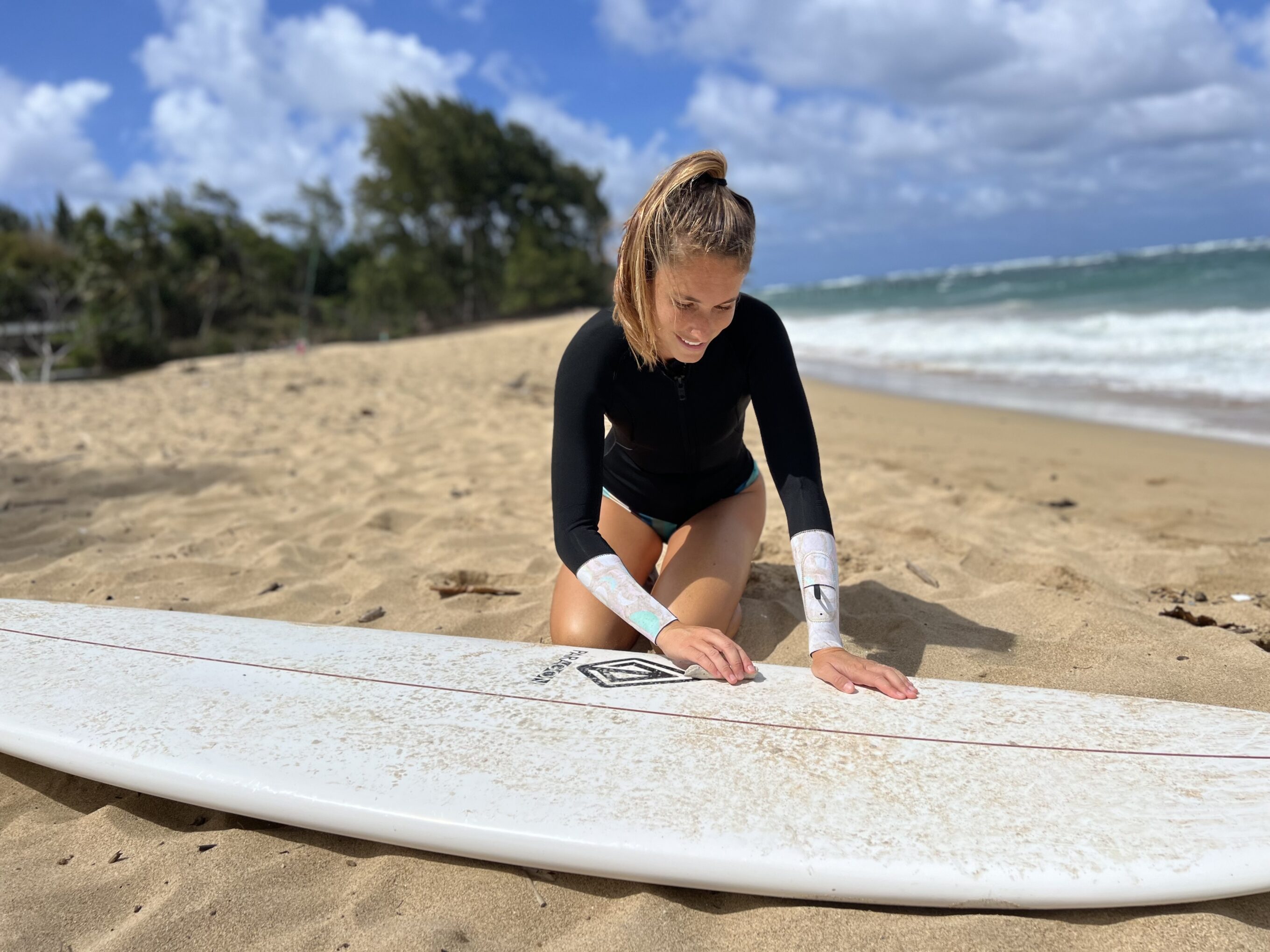 Waxing down a surfboard in a wetsuit jacket.