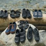 a group photo of the best water shoes we tested in 2023, sitting on a log and rock next to the water.