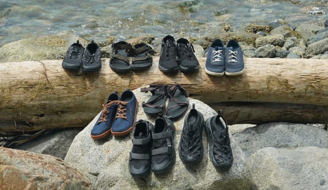 a group photo of the best water shoes we tested in 2023, sitting on a log and rock next to the water.