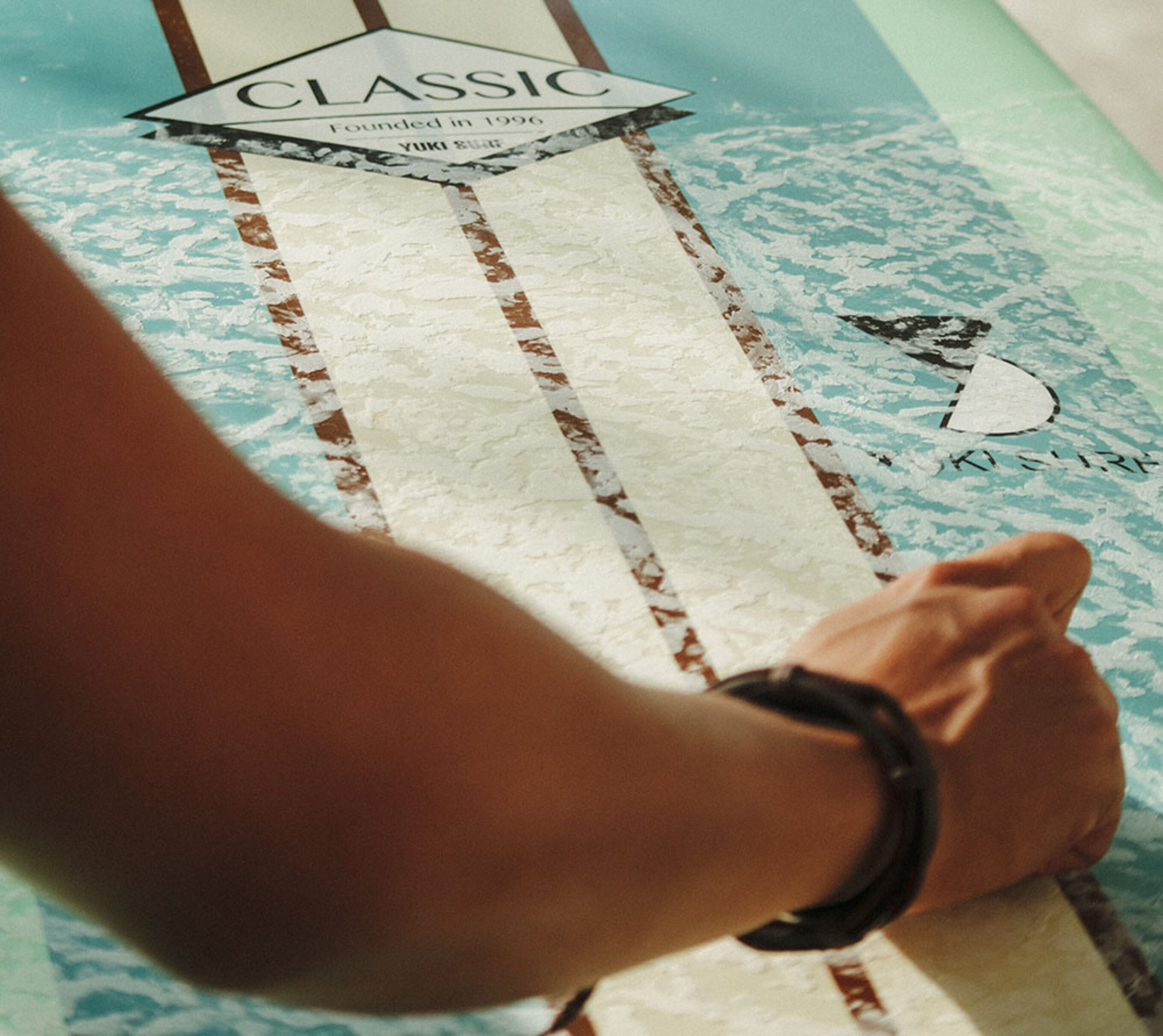 close up of an arm applying surf wax to a longboard