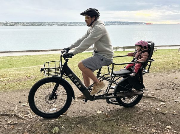 a father and his baby daughter biking by the ocean in the Flyer L885 electric bike