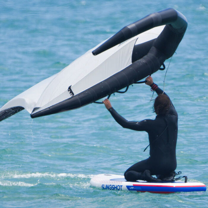 a man learning how to wing foil by starting on his knees on the slingshot ltf board in the water.