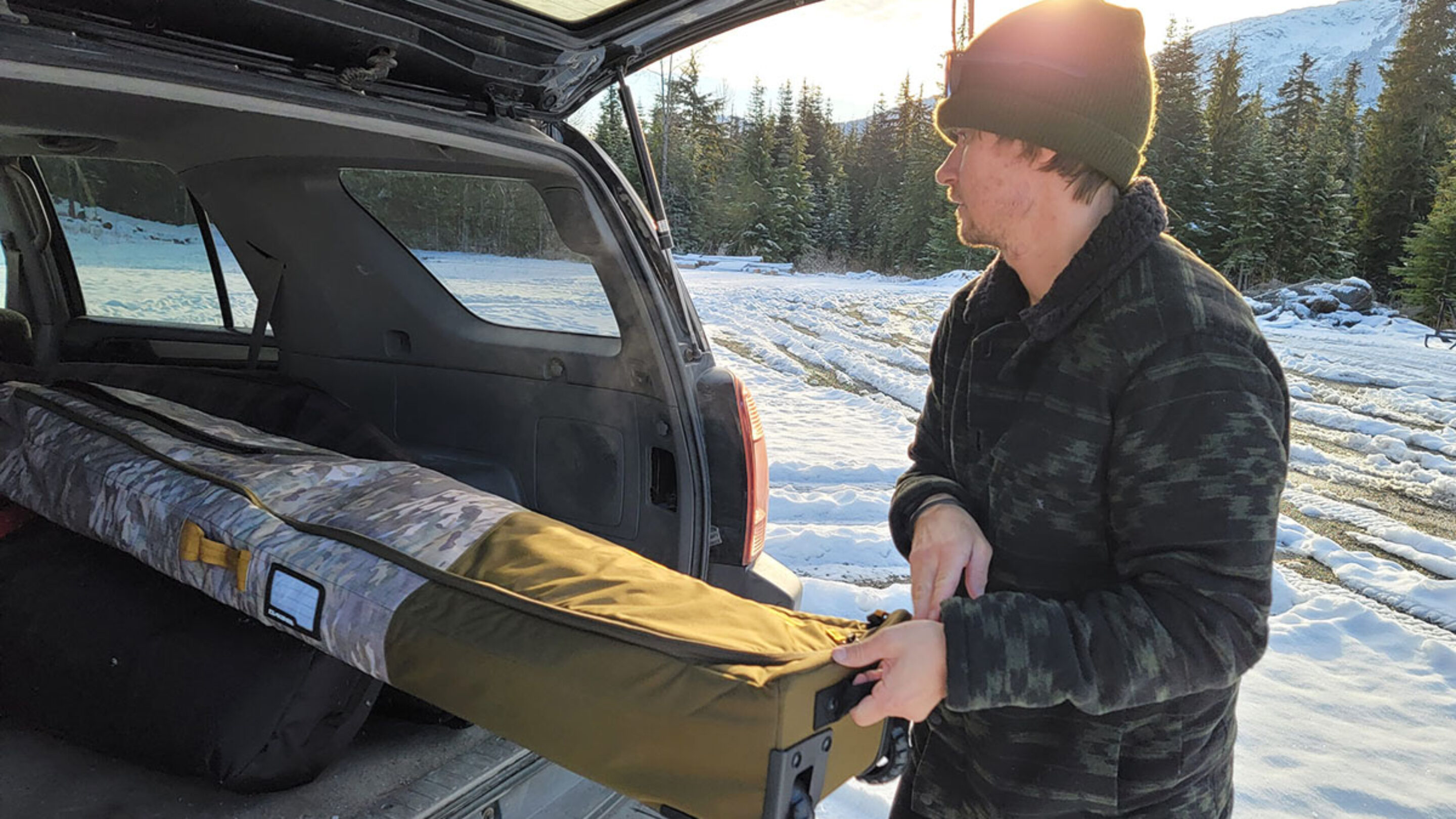 pulling the dakine low roller snowboard bag out of a SUV while testing for the best snowboard bags review