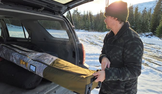 pulling the dakine low roller snowboard bag out of a SUV while testing for the best snowboard bags review