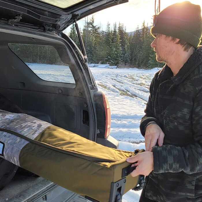 pulling the dakine low roller snowboard bag out of a SUV while testing for the best snowboard bags review