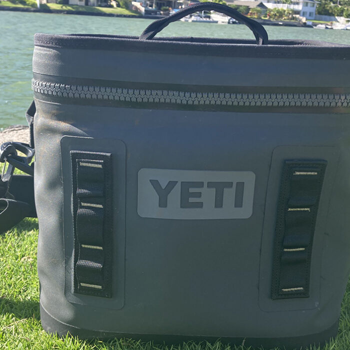 The Yeti Hopper Flip 12 on a green bank with water in the background