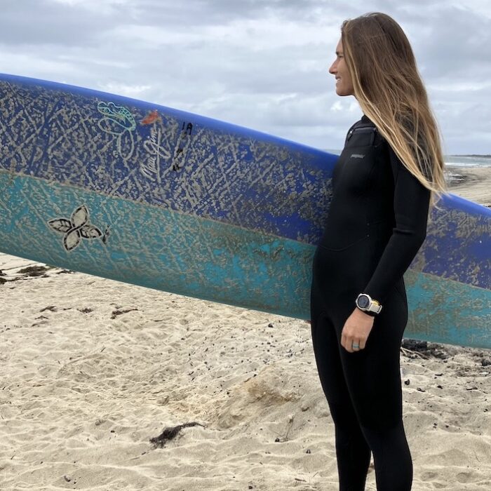 women in a patagonia wetsuit holding a surfboard