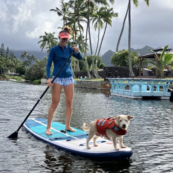 a woman and a dog paddling on a paddle board