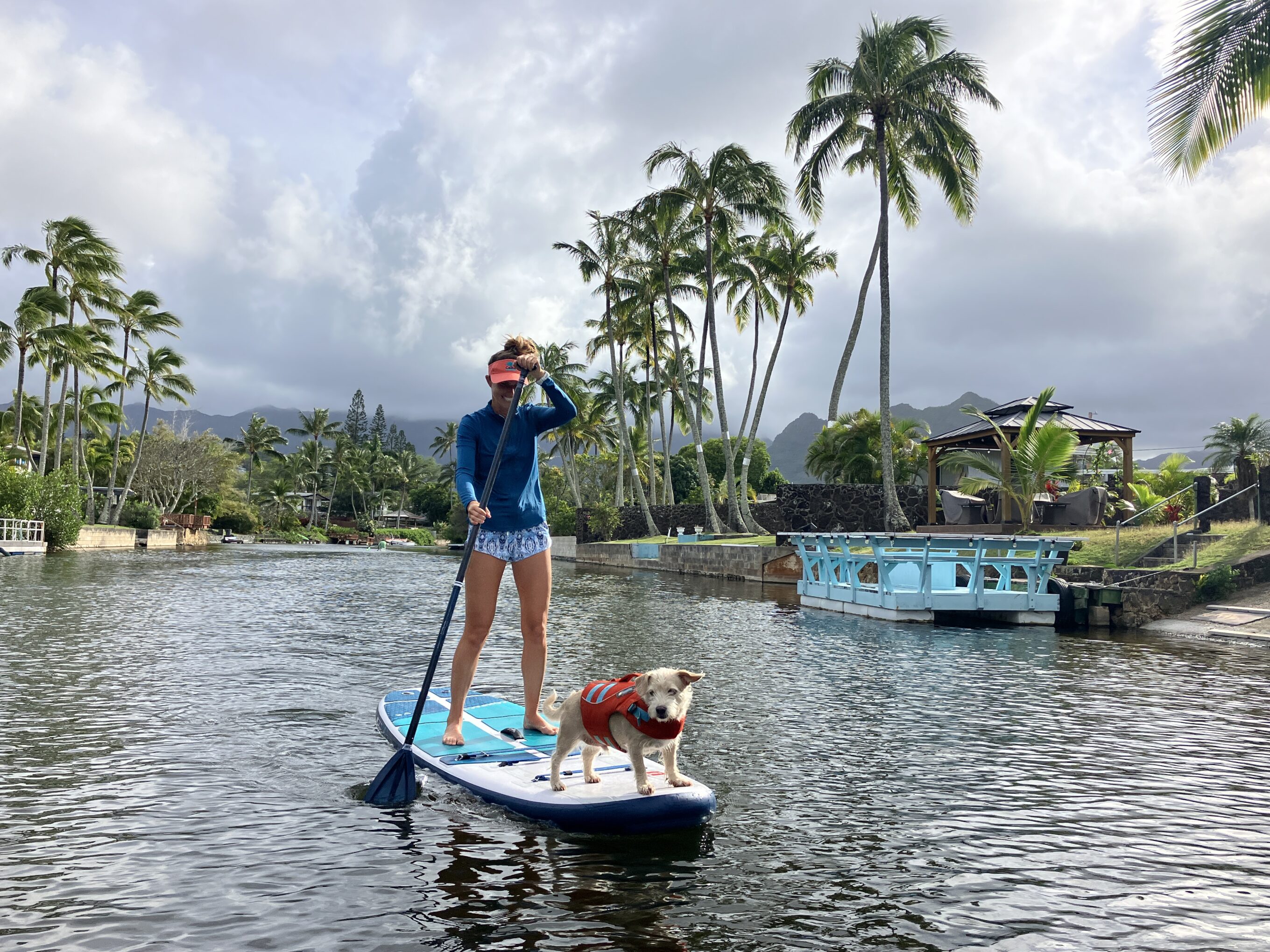 a woman and her dog paddling on an inflatable paddle board