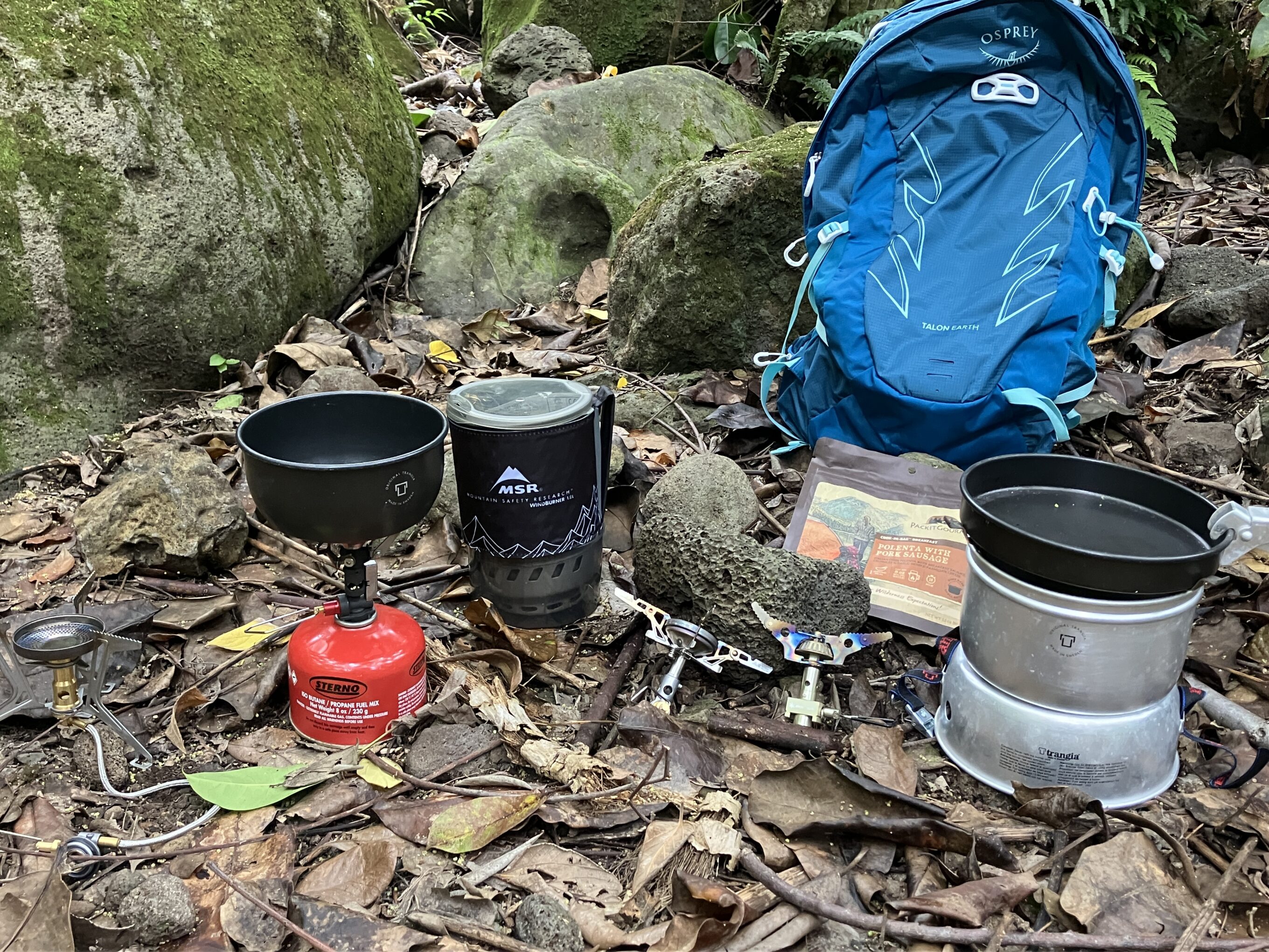 a collection of backpacking stoves sitting on the ground 