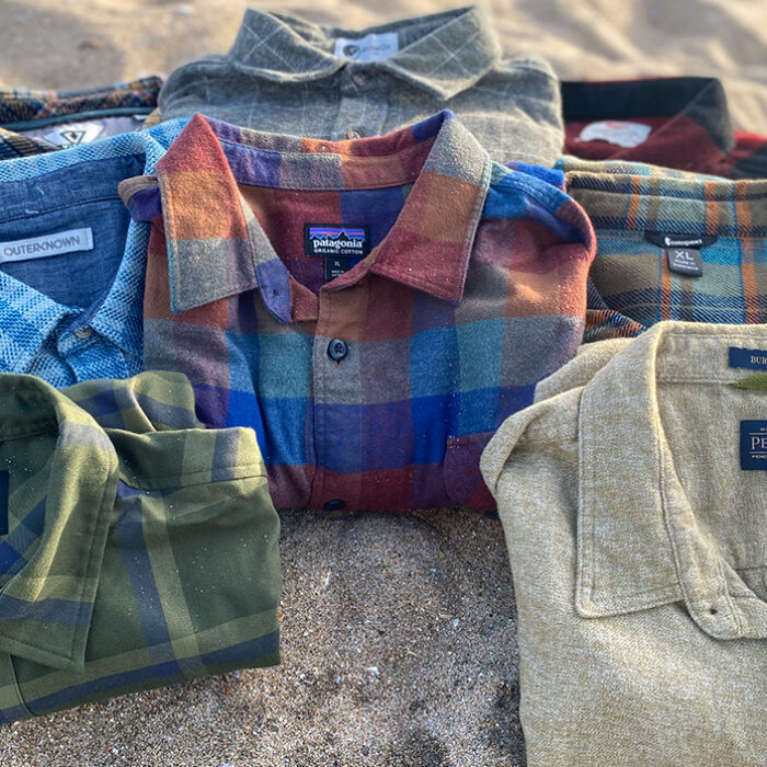 a pile of flannel shirts sitting on the beach