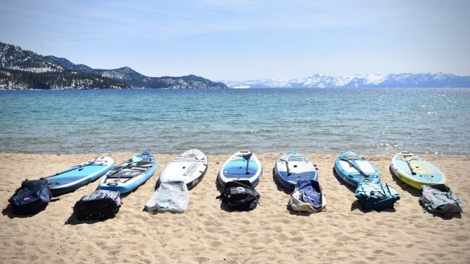 a bunch of inflatable stand up paddle boards lined up on a beach