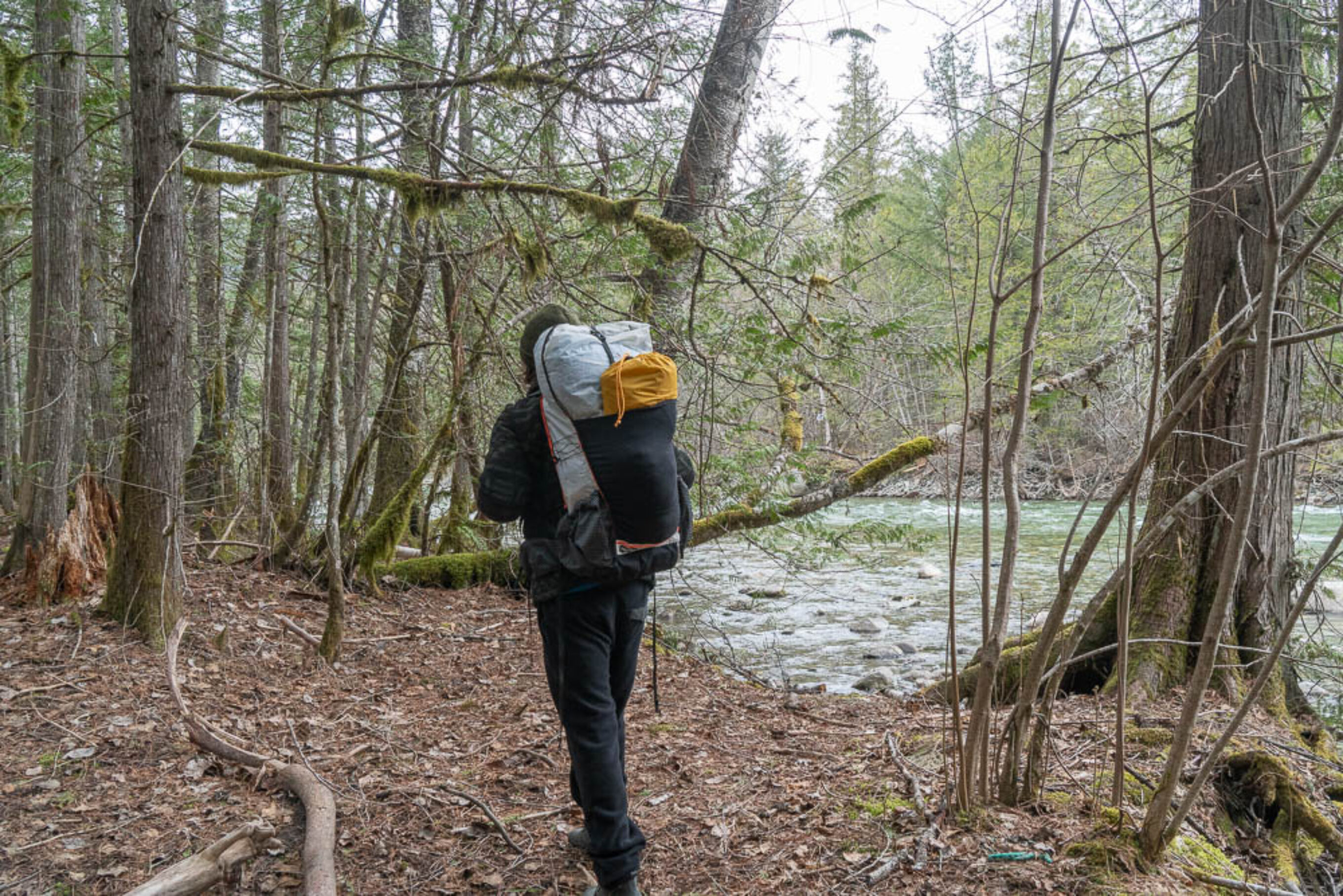 a backpacker hiking next to a river while testing out the best backpacks to review